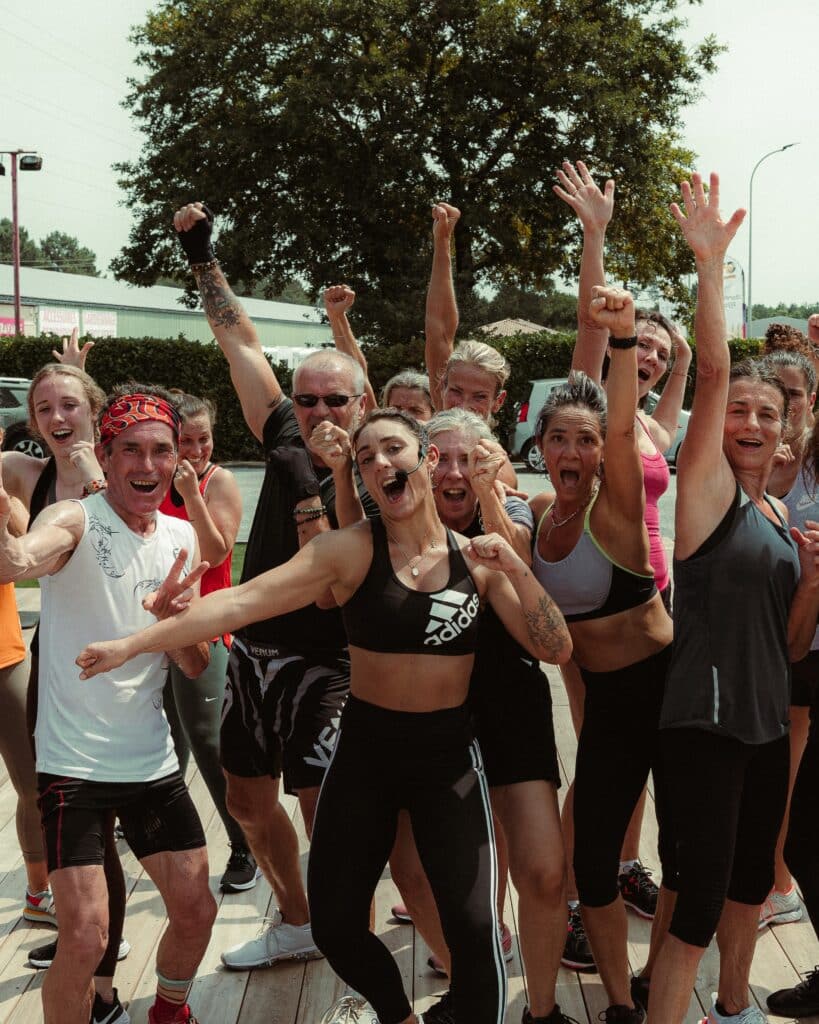 Fitness groupe : Motivation et joie après l'entraînement. Groupe de sportifs joyeux et diversifié. Mains levées, poings serrés et visages radieux célébrant un cours de fitness intense en extérieur.